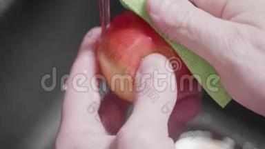 男人`用海绵把红苹果放进水槽里。 清洗水果时使用清洁用品